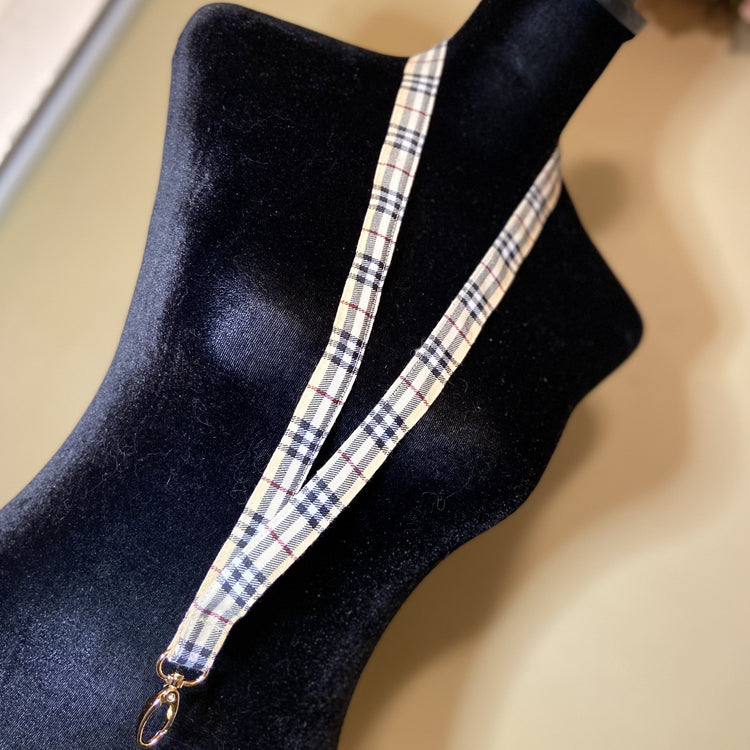 Tartan print lanyard with gold hardware.