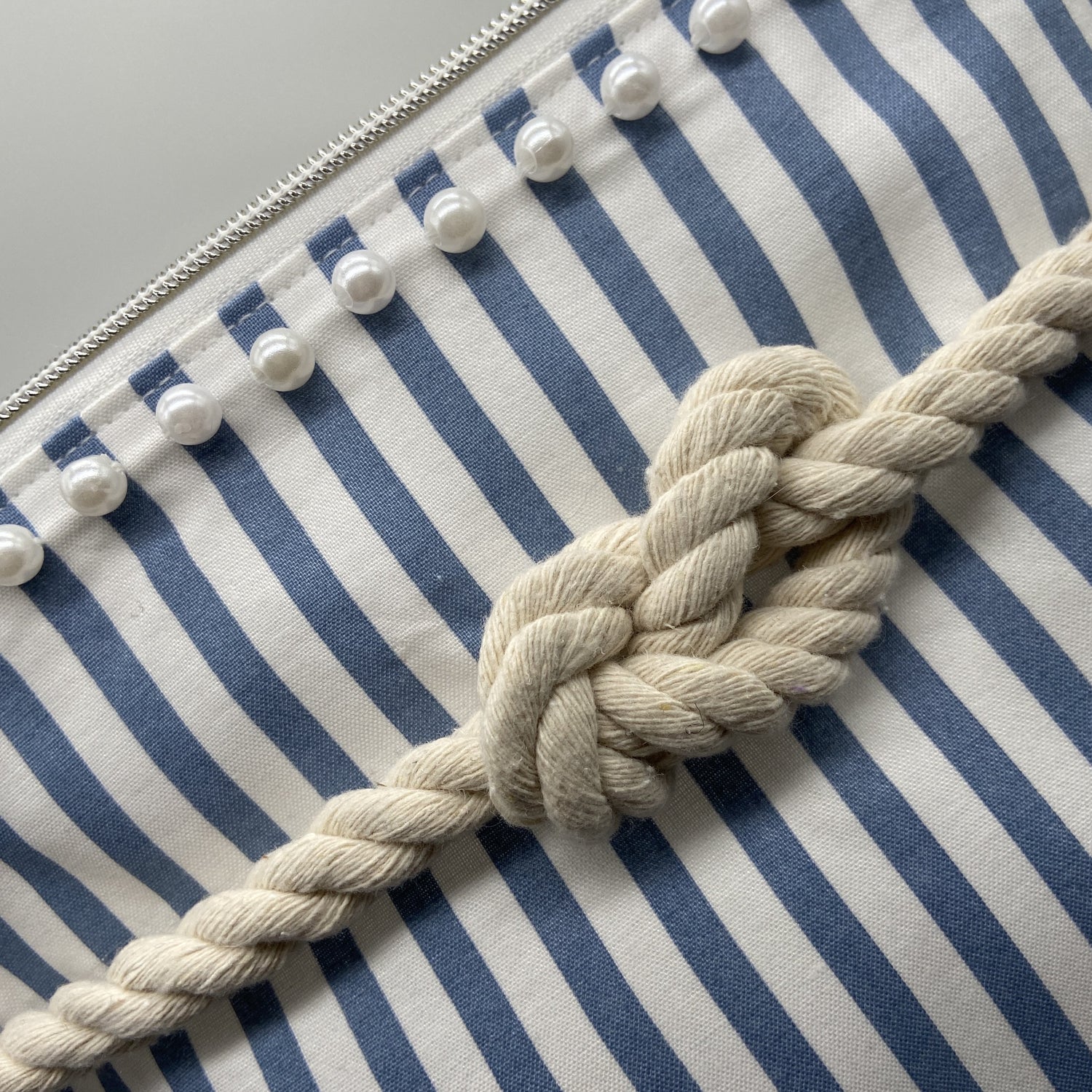Blue and white striped nautical cosmetic bag with a figure 8 rope knot.